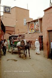 Image du Maroc Professionnelle de  Une calèche passe dans une rue de la médina près du  Cinéma Eden au quartier El Kennaria de Marrakech qui propose deux films à l'affiche La fureur du Dragon avec Bruce Lee film des années soixante-dix et Kalidor, la Légende du talisman qui est un film de Richard Fleischer avec comme acteur principale Arnold Schwarzenegger, Samedi 22 Février 1987. (Photo / Abdeljalil Bounhar)